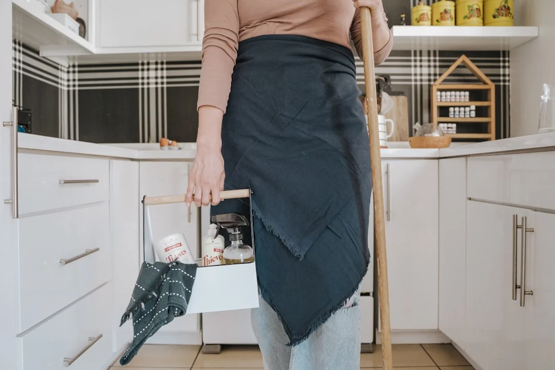 a-woman-in-a-green-shirt-and-black-gloves-vacuuming-a-gray-ottoman-5txz228u4eo